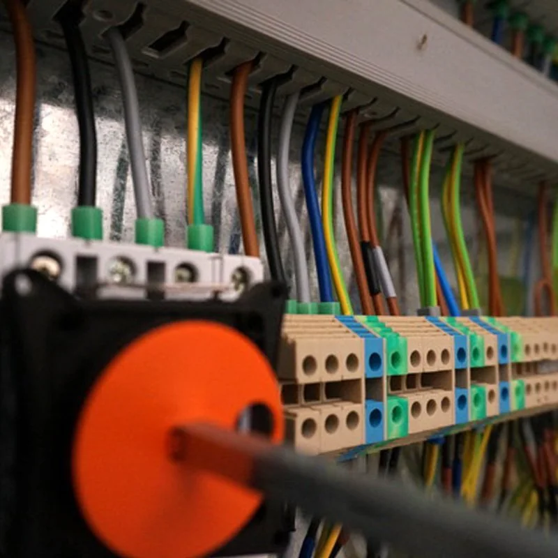 Close-up of an orange rotary isolator beside neatly terminated control-panel wiring, from their gallery